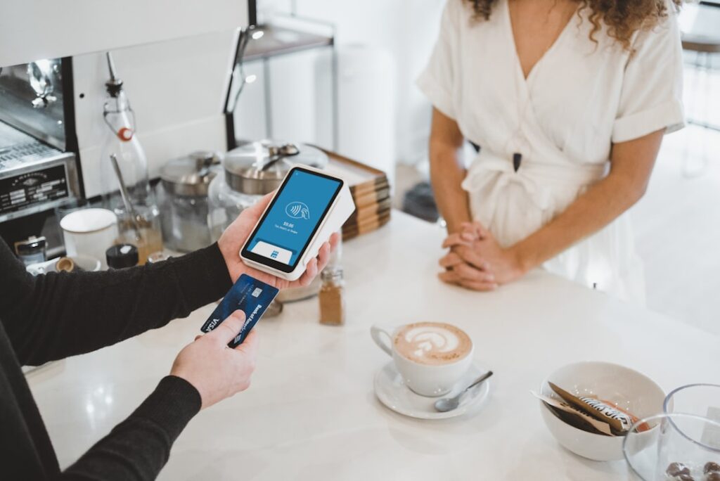 A close-up of a person using a chip card to pay at a small countertop payment terminal in a retail setting.