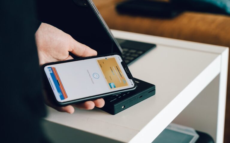 A person using a credit card and a mobile phone to make a payment on a countertop.