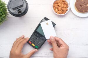 Person reviewing a payment statement beside a card reader, calculator, and printed transaction receipts.